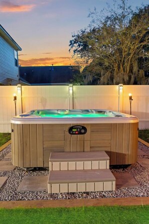 A hot tub with a control panel, surrounded by a wooden deck and a white fence. - NEW! Game Room~HotTub~Fire Pit~.8mi to Old Town (Bluffton)