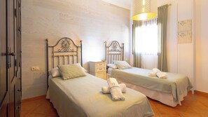 Une chambre d’hôtel avec deux lits, une table de chevet, une lampe et une fenêtre avec des rideaux.