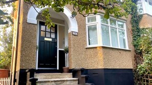 A house with a black front door, a small porch, and a set of stone steps leading to the entrance.