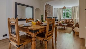 A dining area with a wooden table and chairs, a breakfast setting, and a living room with a sofa and a fireplace.