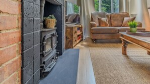 A cozy living room with a brick fireplace, a leather sofa, and a wooden coffee table.