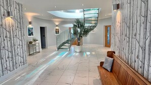A spacious lobby with a marble floor, a wooden bench, a spiral staircase, and a large potted plant. - Whitewater, with expansive sea views and hot tub (Westward Ho!)