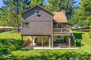 A two-story house with a covered patio, a slide, and a deck.