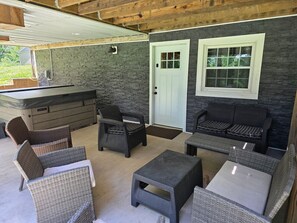 A covered patio area with wicker furniture, a stone wall, and a white door.