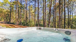 A hot tub surrounded by tall trees in a forested area.