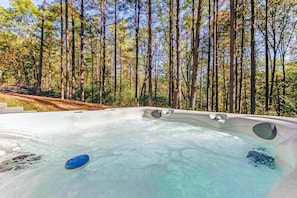 A hot tub surrounded by tall trees in a forested area.