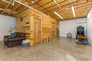 A spacious room with a wooden wall, a brown leather sofa, a wooden bench, and a ping pong table. - Hocking Hills Cabin w/ Hot Tub- near Old Mans Cave (Logan)