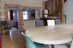 A dining area with a round table, chairs, a lamp, and a brick wall.