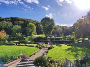 A well-maintained garden with a pathway leading to a seating area, surrounded by lush greenery and trees.