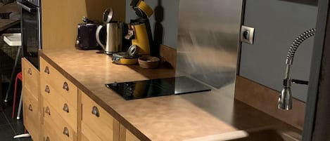 A modern kitchen with wooden cabinets, a stainless steel sink, and various kitchen appliances.