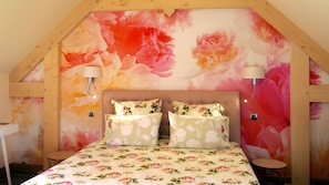 A bedroom with a floral wallpaper, a wooden ceiling, and two bedside lamps.