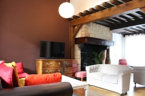 Un salon avec une cheminée, un téléviseur et un canapé blanc.