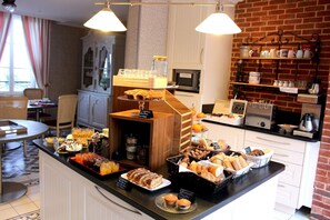 A breakfast buffet with various pastries, breads, and beverages.