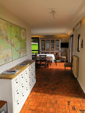 Un coin repas avec un sol en briques, des meubles blancs et une carte accrochée au mur.