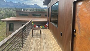 A modern building with a wooden deck, large windows, and a view of mountains. - Cozy studio in charming Ridgway, CO (Ridgway)