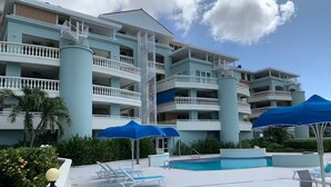A hotel with a pool area, multiple balconies, and blue umbrellas. - Curacao,Piscadera Bay, next to Marriott, Very luxuriously furnished Apartment (Willemstad)