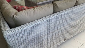 A modern living room with a glass-top coffee table, two grey armchairs, a sofa, a ceiling fan, and a TV mounted on the wall. - Curacao,Piscadera Bay, next to Marriott, Very luxuriously furnished Apartment (Willemstad)