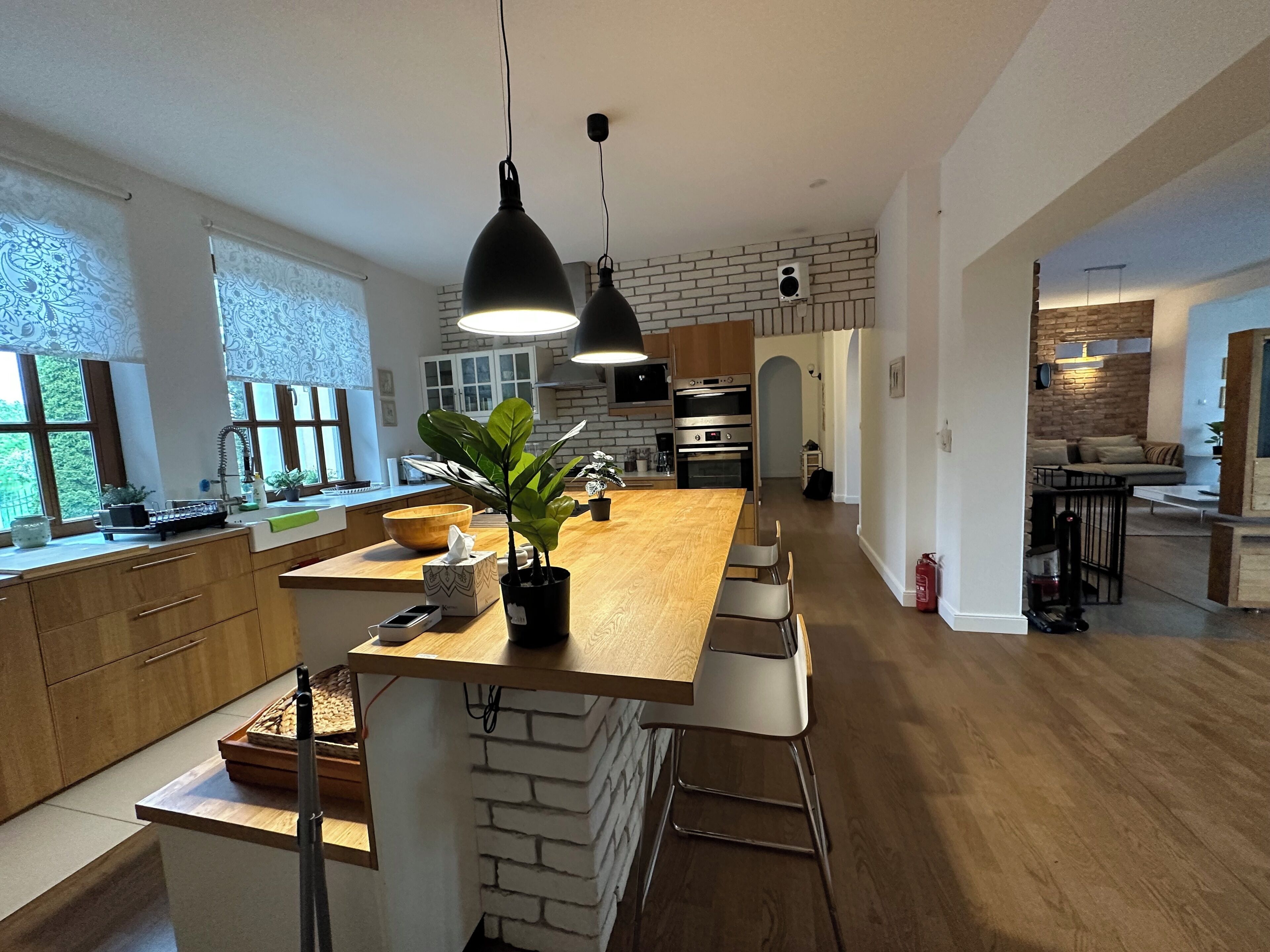 A modern kitchen with a central island, pendant lighting, and a brick accent wall.