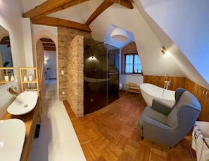 Un baño moderno con una bañera independiente, un cerramiento de ducha de vidrio y un tocador de madera.