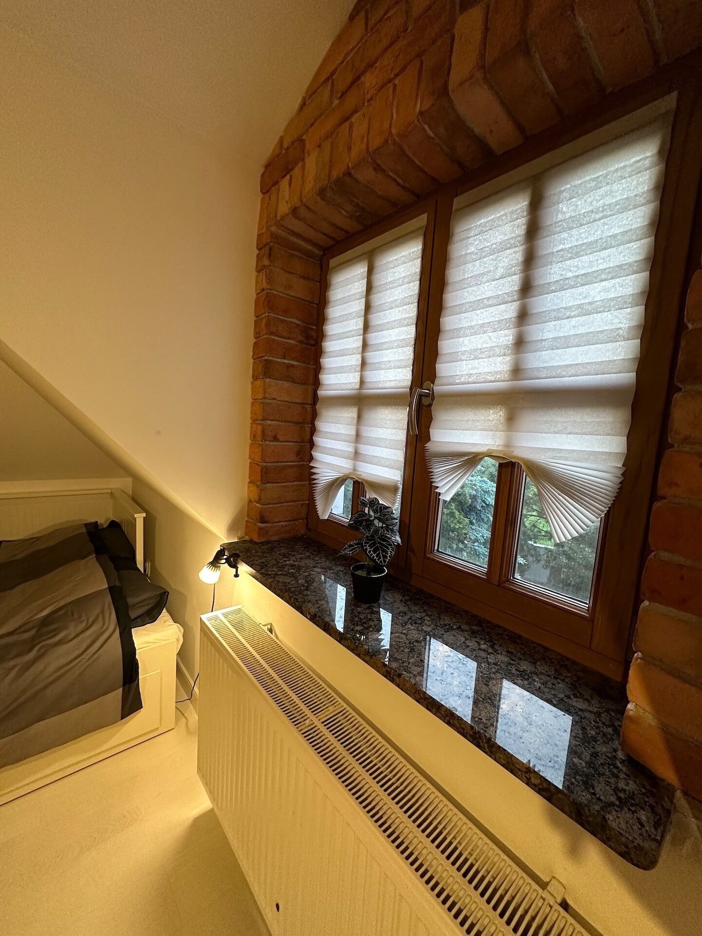 A kitchen with a granite countertop, a radiator, and a window with blinds.
