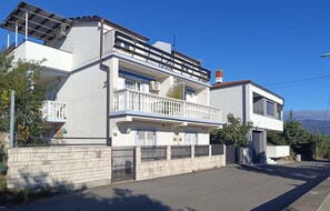A modern two-story residential building with a balcony, a stone wall, and a clear sky. - Amazing apartment in Novi Vinodolski with WiFi (Novi Vinodolski)