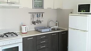 Una cocina moderna con estufa a gas, hervidor, pileta y refrigerador.