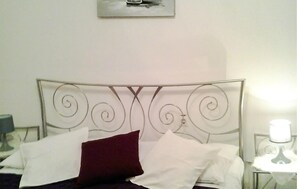 A bed with a metal headboard, white and red pillows, and a bedside table with a lamp. - Amazing apartment in Novi Vinodolski with WiFi (Novi Vinodolski)