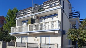 A two-story building with a balcony, a stone wall, and a metal fence. - Awesome apartment in Novi Vinodolski with WiFi (Novi Vinodolski)