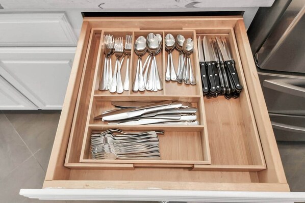 A kitchen drawer with utensils and knives organized in compartments.
