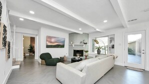 A spacious living room with a large white sofa, a green armchair, and a fireplace. - *Pool | Near Galleria Mall, NRG stadium (Houston)