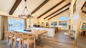 A spacious kitchen with wooden flooring, a central island, and a dining area with wooden chairs.