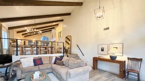 A spacious living room with a sectional sofa, a coffee table, and a dining area in the background.