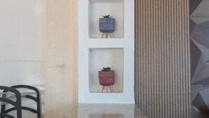 A kitchen with a granite countertop, a hanging copper pendant light, and three shelves with decorative planters. - Apartamento e Deck com vista mar - Loft Rocha (Rio de Janeiro)