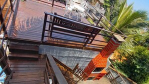 A wooden deck with a metal railing, a white chair, and a small table. - Apartamento e Deck com vista mar - Loft Rocha (Rio de Janeiro)