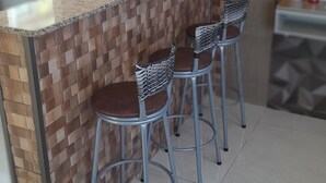 A kitchen with a tiled backsplash, a granite countertop, and three bar stools with zebra-patterned seats. - Apartamento e Deck com vista mar - Loft Rocha (Rio de Janeiro)