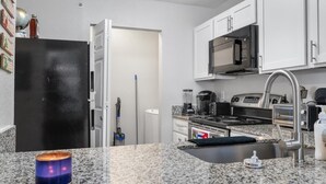 A kitchen with white cabinets, a black refrigerator, a microwave, a stove, and a sink. - THE LITTLE HAVANA AT RIVERSIDE #11 (Austin)