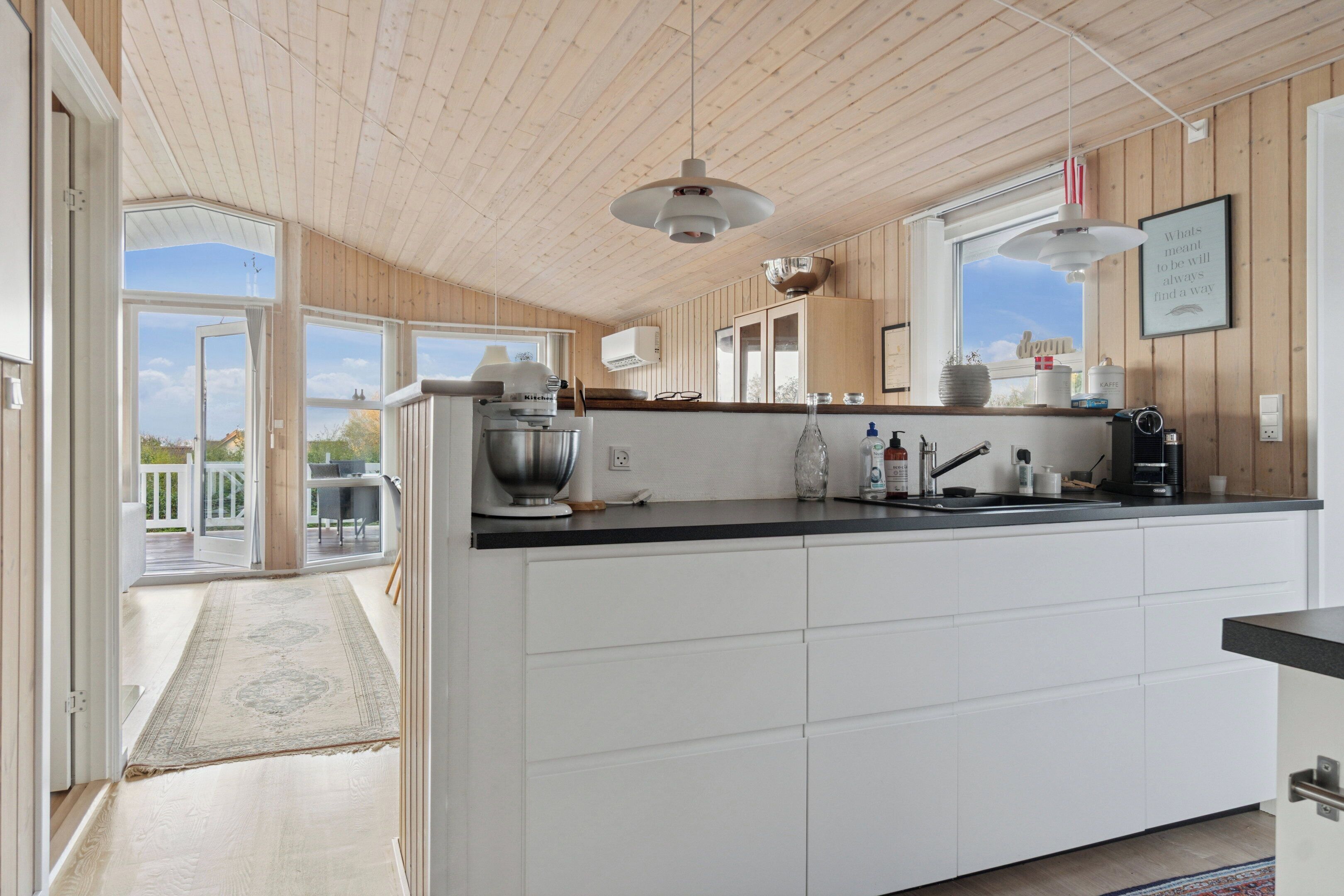 Una cocina moderna con una isla grande, techo de madera y vistas al exterior.