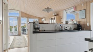 A modern kitchen with a large island, wooden ceiling, and a view to the outside. - Active coastal holiday in cozy cottage (Slagelse)