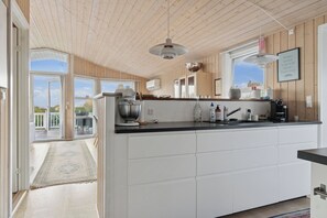 A modern kitchen with a large island, wooden ceiling, and a view to the outside. - Active coastal holiday in cozy cottage (Slagelse)