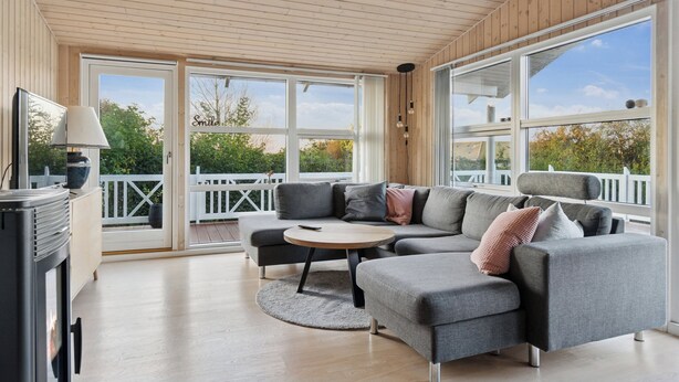 A modern living room with a sectional sofa, a round coffee table, and a fireplace. - Active coastal holiday in cozy cottage (Slagelse)