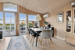A modern kitchen with a large dining table, wooden walls, and a view of the outdoors. - Active coastal holiday in cozy cottage (Slagelse)