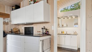 A modern kitchen with white cabinets, a black countertop, and a visible stove. - Active coastal holiday in cozy cottage (Slagelse)