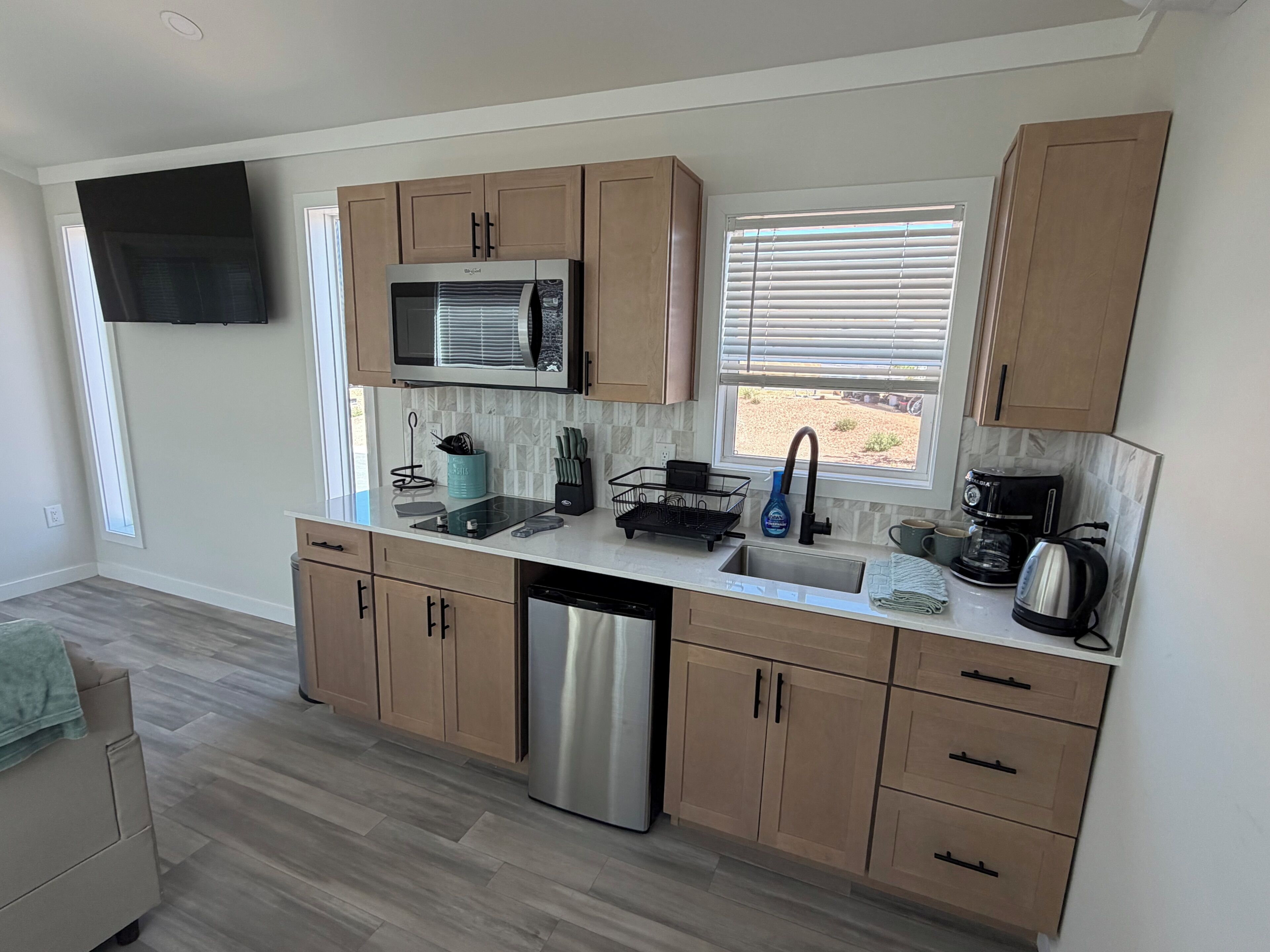 A modern kitchen with wooden cabinets, a stainless steel dishwasher, a microwave, and a coffee maker.