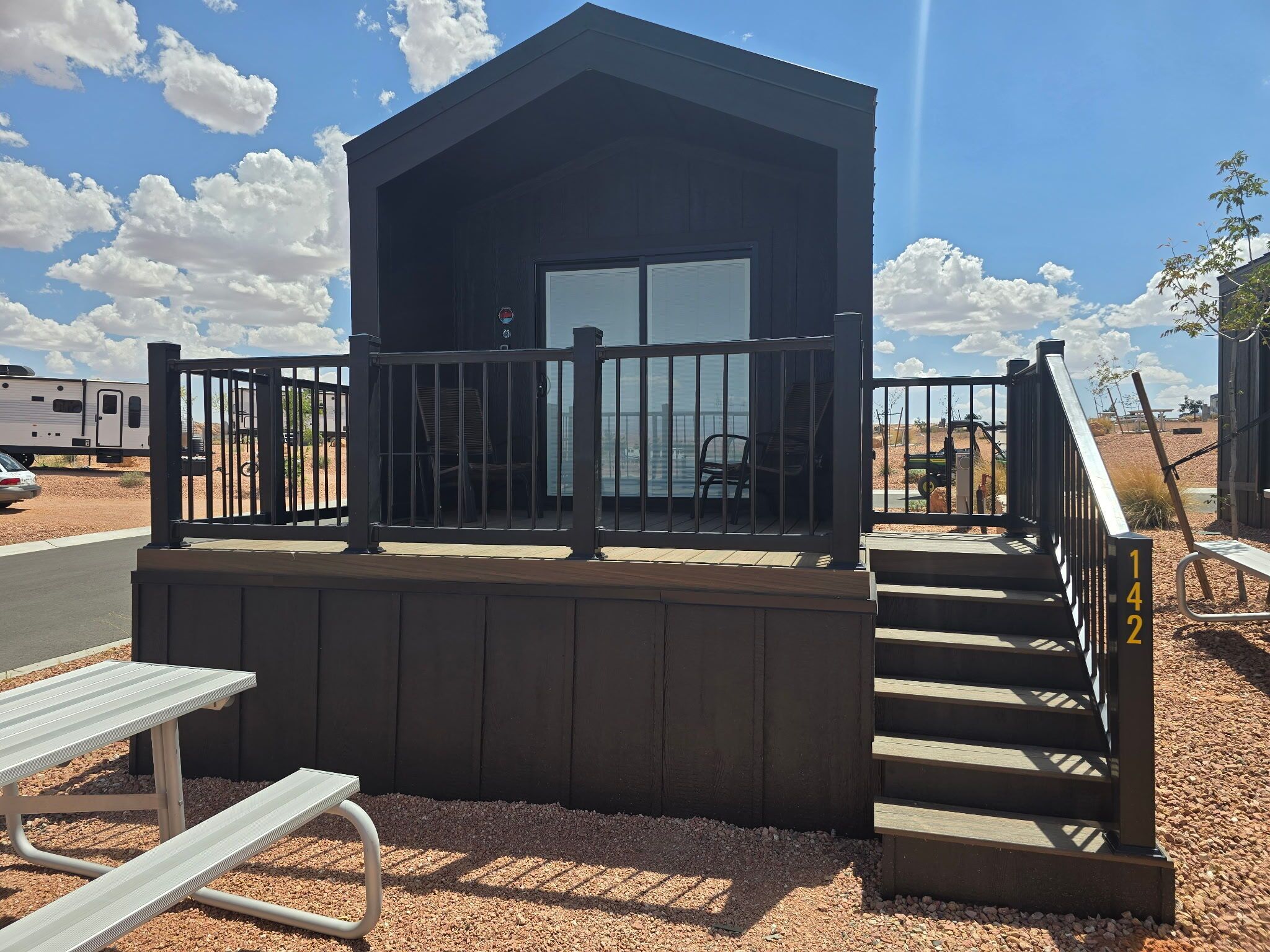 A small wooden cabin with a balcony, a bench, and a staircase leading to the entrance.