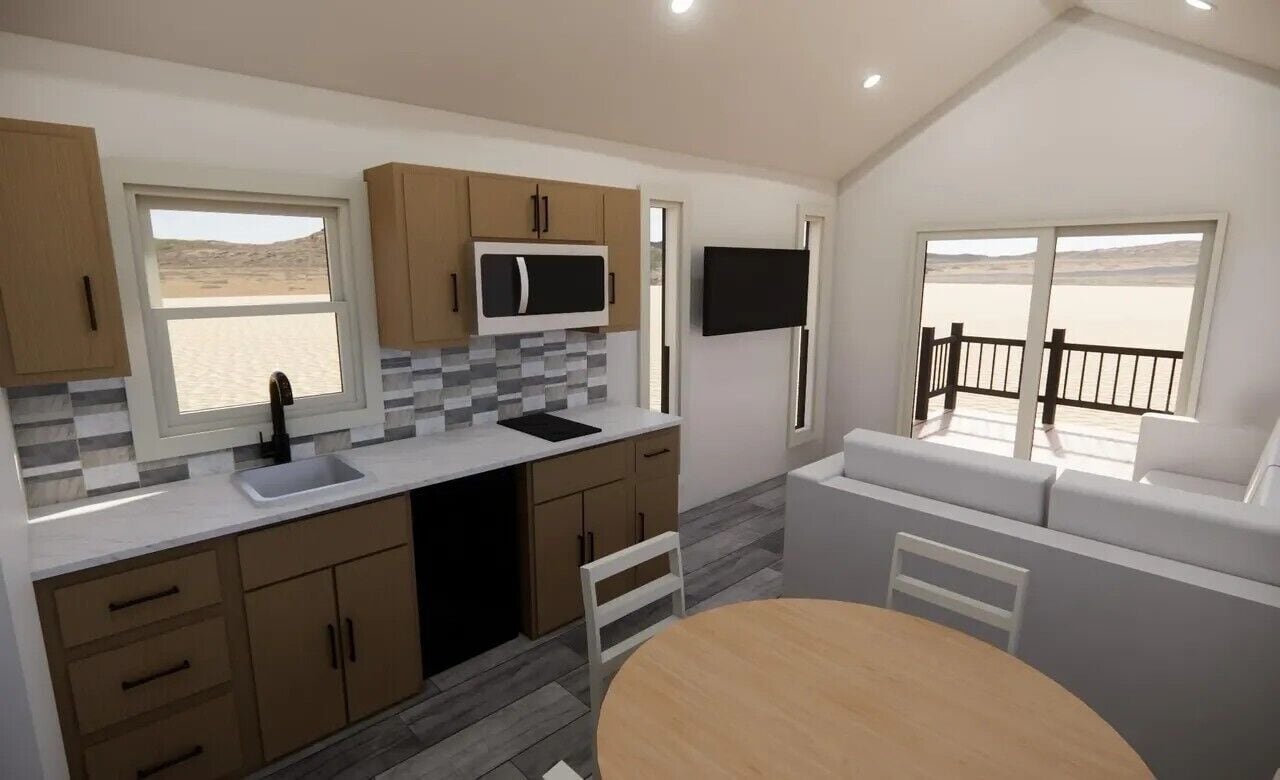A modern kitchen with a large window, a dining area with a round table, and a TV mounted on the wall.