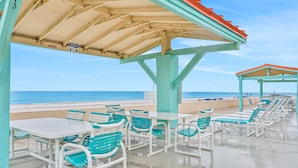 Un caffè sulla spiaggia con posti a sedere all'aperto, una zona coperta e vista sull'oceano.