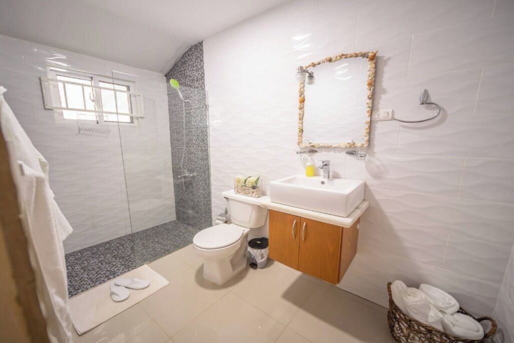 Une salle de bain équipée d’une douche, de toilettes, d’un lavabo et d’un miroir.