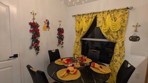 A dining area with a round table, black chairs, and a chandelier. - Magical World (Davenport)
