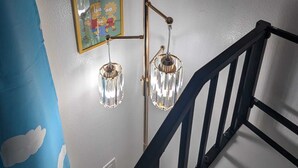 A staircase with a black railing, a wall with two framed pictures, and a blue wall with cloud patterns. - Magical World (Davenport)