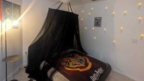 A bedroom with a canopy bed, a decorative ceiling light, and wall-mounted fairy lights. - Magical World (Davenport)